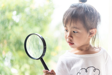 Asian child girl looking with magnifying glass