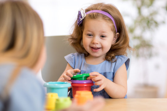 Kid girl playing stacking cups at home