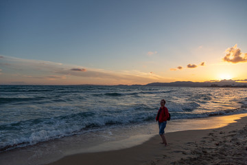 Obraz premium Older woman enjoying beautiful sunset on a beach.