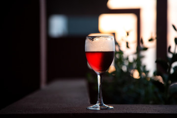 Red wine glass over sunset background. Close-up, side view