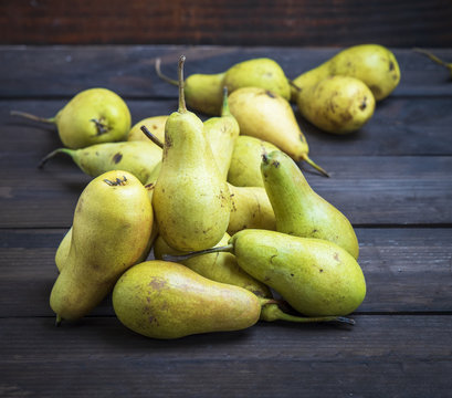 ripe green pears on a brown wooden background