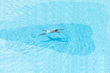 Aerial  view on the men in the swimming pool with transparent blue water. In the motion