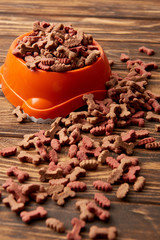 selective focus of plastic bowl with pile of dog food on wooden table