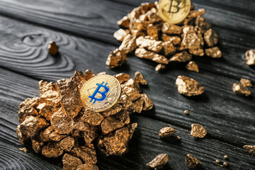 Gold nuggets and bitcoins on dark wooden background