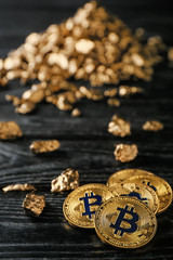 Bitcoins and gold nuggets on dark wooden background