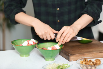 Woman preparing tasty salad with avocado in kitchen
