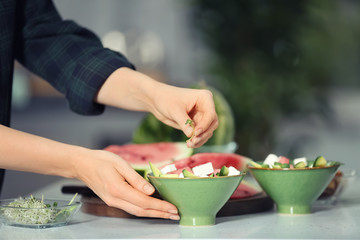 Obraz na płótnie Canvas Woman preparing tasty salad with watermelon in kitchen