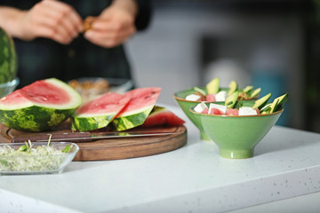 Ripe watermelon and bowls with fresh salad on kitchen table
