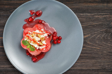 Plate with delicious watermelon salad on wooden table, top view
