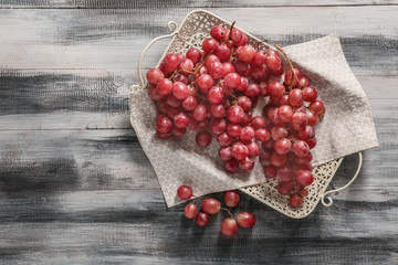 Tray with red grapes on wooden table