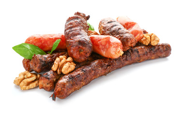 Delicious grilled sausages with walnuts on white background