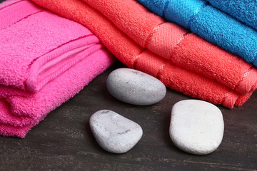 Soft towels with spa stones on dark table