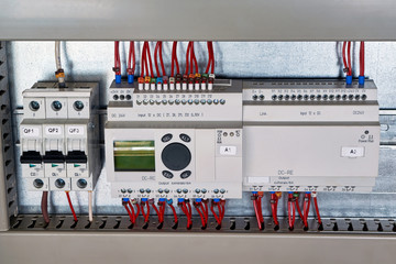 In the electrical Cabinet circuit breaker, control relay, expansion unit. Controller with liquid crystal display. The wires are connected to modular electrical equipment. Modern automation.