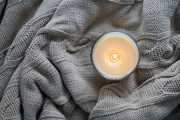 Beautiful burning candle on warm plaid