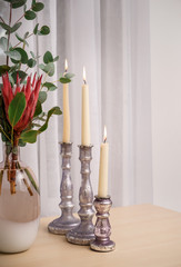 Burning candles with beautiful bouquet in vase on wooden table