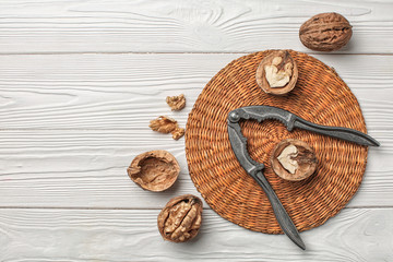 Tasty walnuts with nutcracker on white wooden table