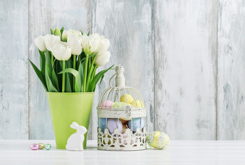 Vintage bird cage full of colorful Easter eggs and spring flowers