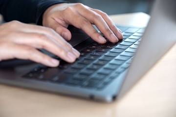 Closeup image of hands using and typing on laptop keyboard on table