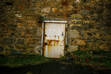 romantic nostalgic decay white door with rust in a massive stone wall with grass porch travel concept tourism landscape 