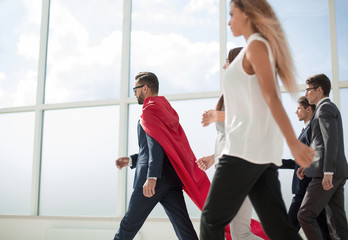 businessman superhero and his business team walking in office
