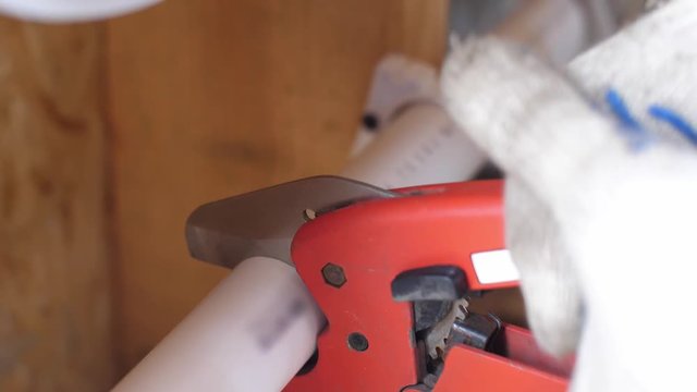 Cutting plastic pipe with special scissors. 4k slow motion. Plumbing work in the construction of a frame house. Connection of water pipe parts. Close up