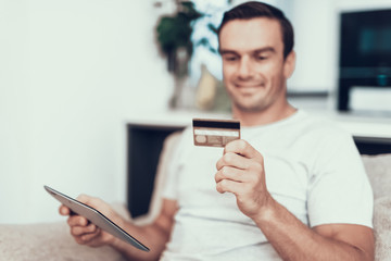 Blurred Person Holds Credit Card and Uses Tablet