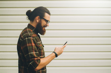 Young cheerful bearded hipster man using phone