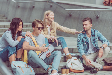 young tourists resting on steps on street of new city