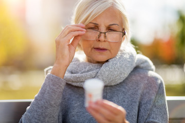 Senior woman taking prescription medicine outdoors
