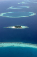 Blue and turqouise coral reef surrounding a small island, in the Maldives, aerial view, panorama...