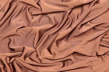 Background and texture. The concept of a hobby and production. Image of the texture of the fabric for sewing clothes. Light brown knitwear, silk. Abstraction. Cropped shot, isolated, close-up, blurred