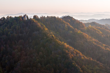 Church on top of rolling forest hills in autumn colors illuminated with soft sunlight early morning 