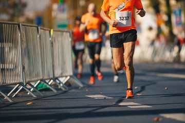 Marathon running race, people feet on autumn road. Runners run urban marathon in the the city