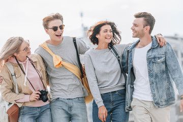 young happy tourists hugging and walking in city