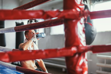 Male boxer drinking water after fight or workout exercising