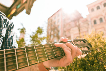 Difficult chord. Close up of male young hands holding chords and man playing on street