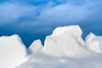 Fototapeta na wymiar Close-up white snow lumps against blue sky. 