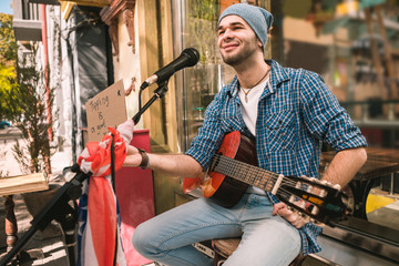 Improve your karma. Pleased male musician carrying cardboard with inscription and smiling