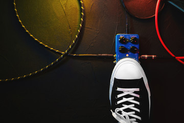 Close up of guitar player foot pressing pedal. Musician uses music effect loop machine. Man in trendy sneakers, his foot playing at stage during concert. Macro view. Copy space