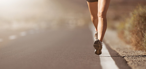 Female legs close up of a woman running on a road with sports shoes 