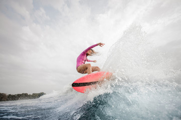 Active girl jumping on the orange wakeboard