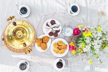 Top view of a table laid with samovar, coffee cups, sweets
