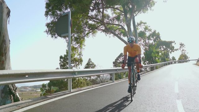 A man on a sports road bike rides on the road located high in the mountains. in slow motion.