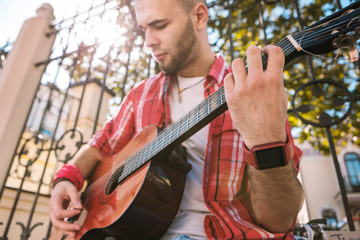 Play mindful. Low angle of focus street musician using guitar and becoming professional