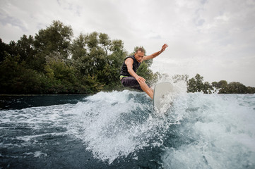 Active man riding on the wakeboard on the high wave