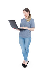 Young happy girl in casual clothes is standing with a laptop, isolated on white background