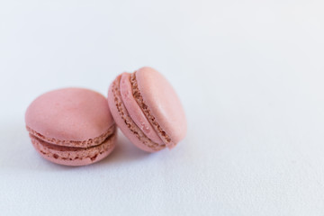 Two pink macarons stacked on a white illuminated background