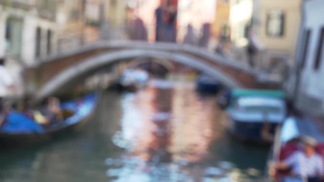 Skillful gondolier paddles boat with tourists under short bridge in Venice Italy People walking across arched bridge over narrow canal while tourists ride boats 4k