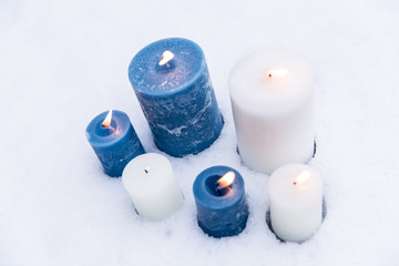 Blue and white candles flaming on snow