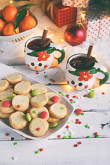 Christmas and new year holiday celebration concept background. Mug of mulled wine with spices, homemade nut cookie, shortbread, xmas tree decoration on wooden table.